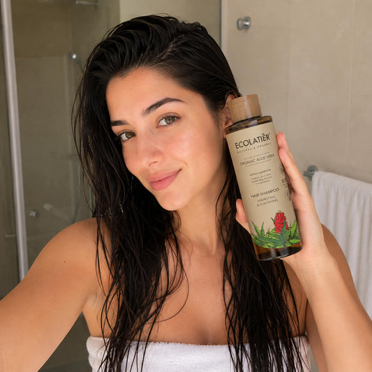 Mujer usando el champú natural Ecolatier del Ritual Capilar Esencial de Nativva en el baño